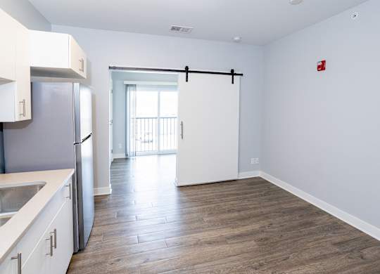 A kitchen with white cabinets and a wooden floor.