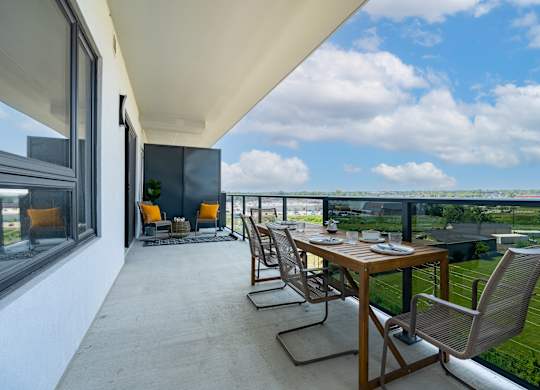 A patio with a table and chairs overlooking a grassy field at Damask, Windsor, N8S 0B7