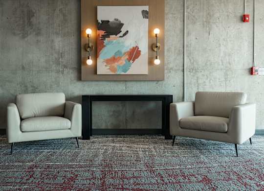 Two chairs and a table are in front of a wall with a painting and lights at Damask, Ontario, N8S 0B7