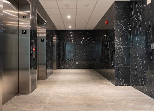 A long hallway with marble floors and walls and elevators on the side at Damask, Windsor, N8S 0B7