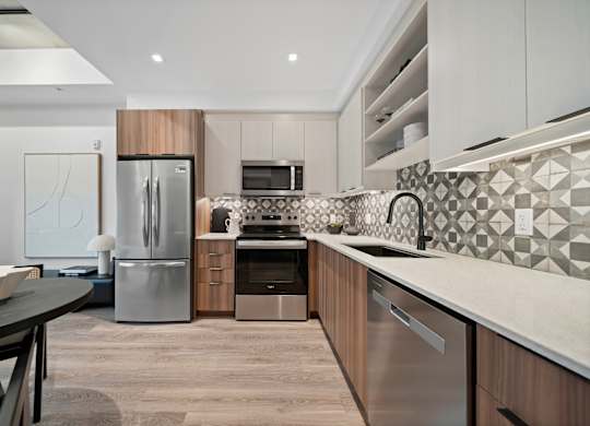 A modern kitchen with a stainless steel refrigerator and a black and white tiled backsplash