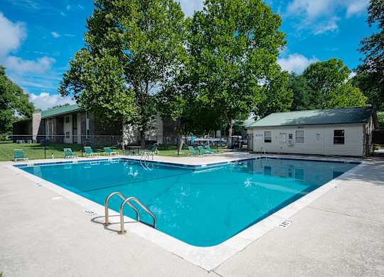 A large swimming pool surrounded by trees and buildings at Sawbranch Apartments, Summerville, SC