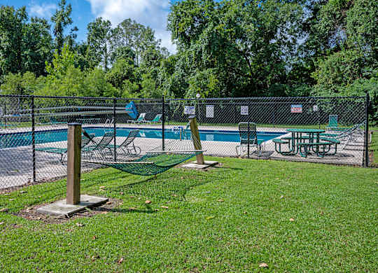 A pool area with a fence and a table and chairs at Sawbranch Apartments, South Carolina