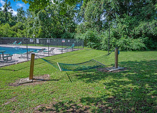 A tennis court is surrounded by a fence and trees at Sawbranch Apartments, South Carolina, 29485