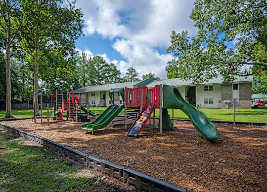 A playground with a green slide and red and green swings at Sawbranch Apartments, Summerville, SC