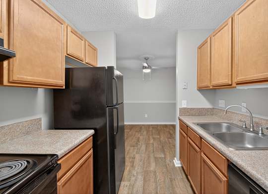A kitchen with wooden cabinets and a black refrigerator at Sawbranch Apartments, South Carolina, 29485