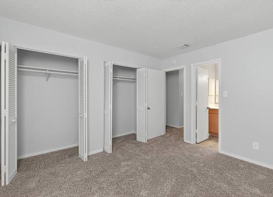 A room with white walls and carpeted floor with three open closets at Sawbranch Apartments, Summerville 29485