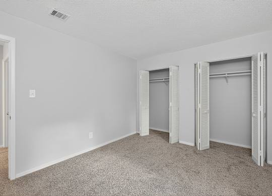 A room with white walls and carpeted floor with three open closets at Sawbranch Apartments, Summerville