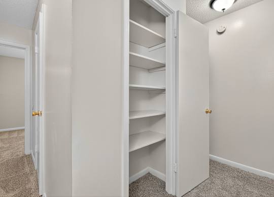 A white closet with shelves and a carpeted floor at Woodlocke Apartments, South Carolina