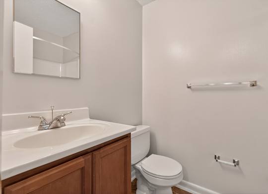 A white toilet sits next to a sink in a small bathroom at Woodlocke Apartments, South Carolina, 27461