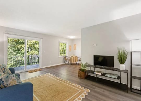 A living room with a blue couch and a television at The Preserve at Pine Valley Apartments, North Carolina