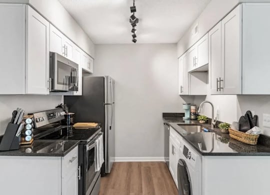 A kitchen with white cabinets and black appliances at The Preserve at Pine Valley Apartments, Wilmington, 28412