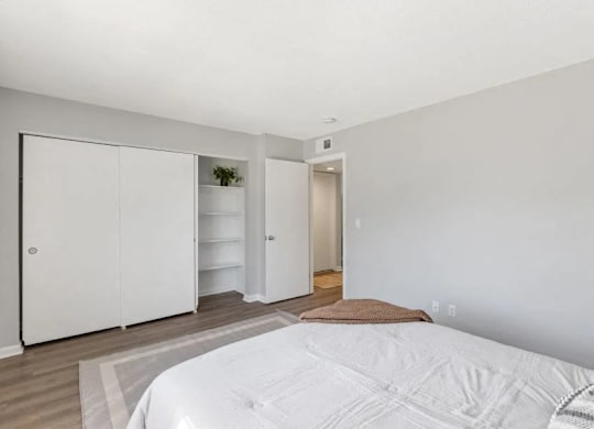 A white bed with a white comforter in a room with white walls at The Preserve at Pine Valley Apartments, Wilmington, North Carolina