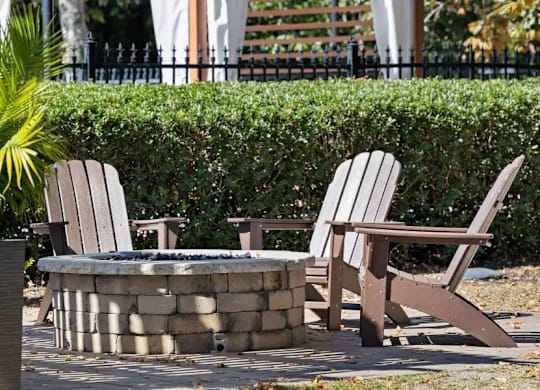 Two chairs and a table are in front of a hedge at The Preserve at Pine Valley Apartments, Wilmington, 28412