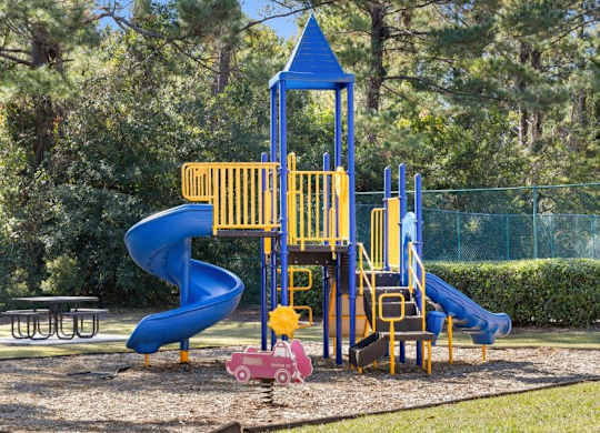 A playground with a blue and yellow slide and a pink car at The Preserve at Pine Valley Apartments, Wilmington