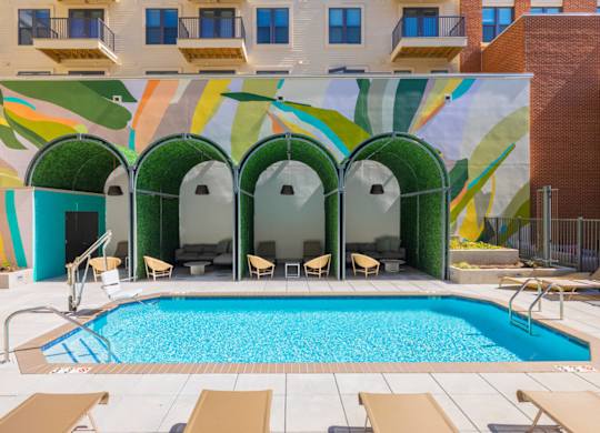 A pool surrounded by chairs and a building with a mural on the side.at The Vale at the Parks, District of Columbia  
