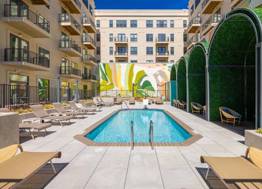 A pool surrounded by lounge chairs and umbrellas.at The Vale at the Parks, Washington, DC 20012  
