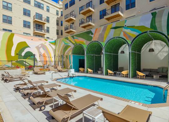 A pool surrounded by sun loungers and a building with a mural on the side.at The Vale at the Parks, Washington, 20012  