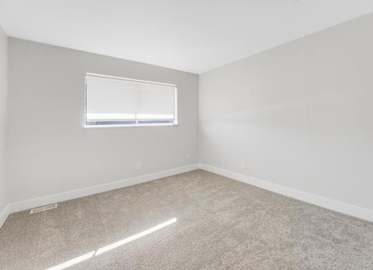 A room with a carpeted floor and a window. at The Lex At Lowry, Denver, Colorado