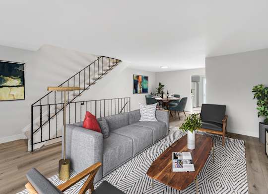 A living room with a grey couch, a coffee table, and a staircase. at The Lex At Lowry, Denver, CO, 80224