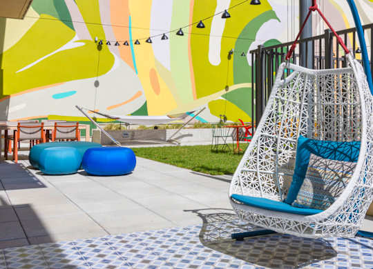 A white hanging chair with blue cushions is in the foreground of a colorful mural.at The Vale at the Parks, Washington, DC  