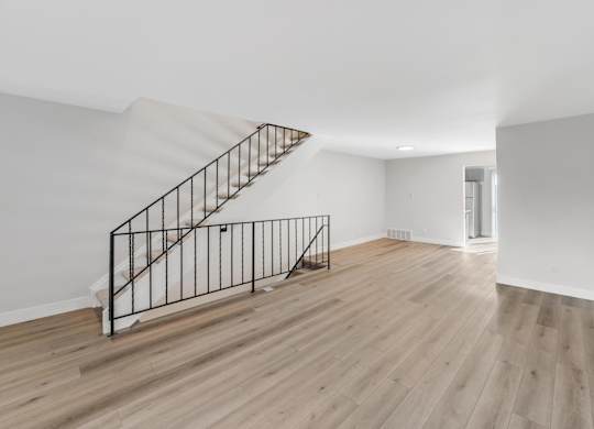 A wooden staircase with a metal railing leads to a second floor. at The Lex At Lowry, Denver, Colorado