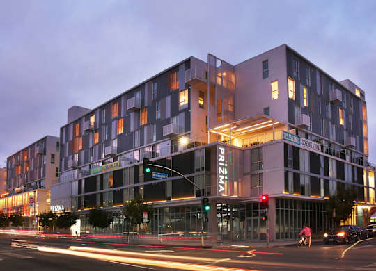 A modern building with a glass facade and a lit up sign that reads at Prizma, California  