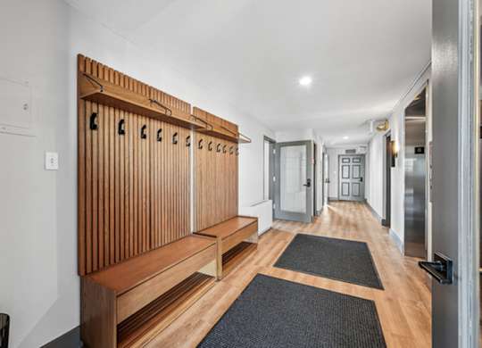 A long hallway with a bench and a door at the end. at The Lex At Lowry, Denver, 80224