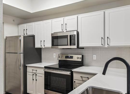 A kitchen with white cabinets and black appliances.at Onyx183, Austin, TX  
