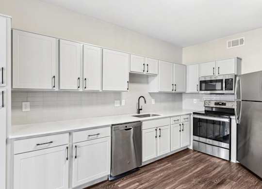 A kitchen with white cabinets and stainless steel appliances.at Onyx183, Austin  