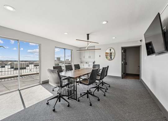 A conference room with a table, chairs, and a television. at The Lex At Lowry, Denver, CO
