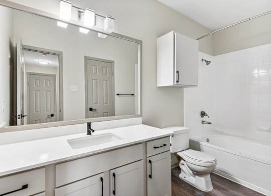 A white bathroom with a sink, toilet, and bathtub.at Onyx183, Austin  