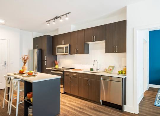 A modern kitchen with a white countertop and dark brown cabinets.at The Vale at the Parks, Washington, 20012  