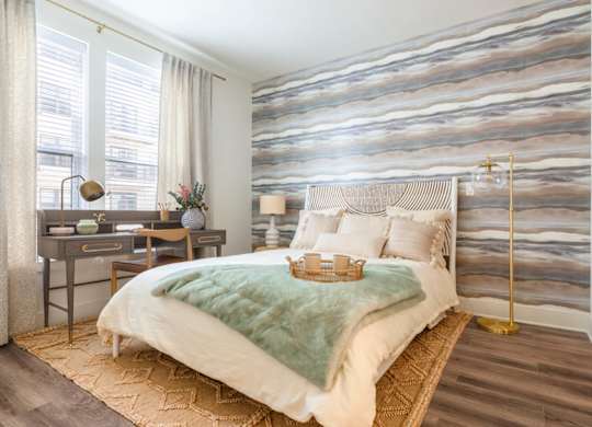A bedroom with a large bed and a desk with a lamp.at The Vale at the Parks, Washington, DC  