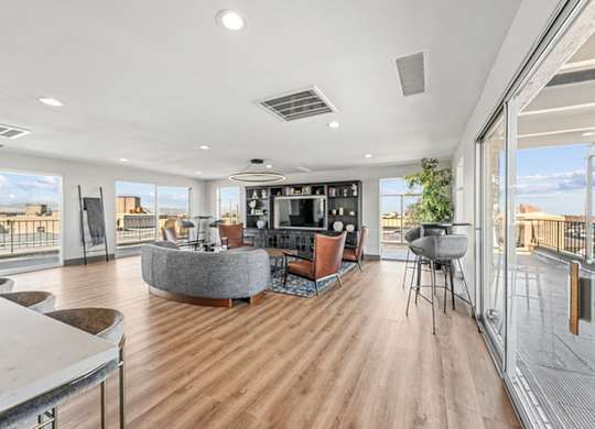A modern living room with a curved sofa and a television. at The Lex At Lowry, Denver, CO