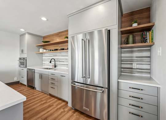A modern kitchen with a stainless steel refrigerator and wooden shelves. at The Lex At Lowry, Denver