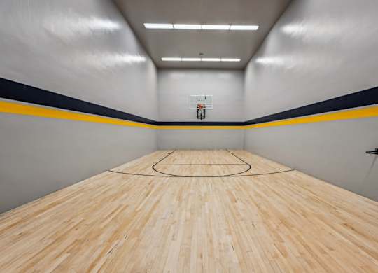 A basketball court with a wooden floor and a basketball hoop. at The Lex At Lowry, Denver, CO, 80224