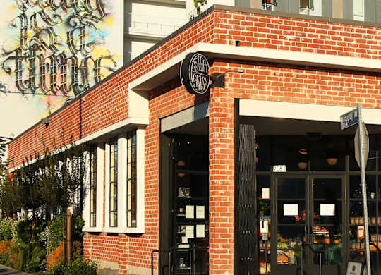 A storefront with a large mural on the side of a building.at Prizma, Los Angeles  