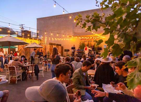 A group of people are sitting at tables outside a restaurant.