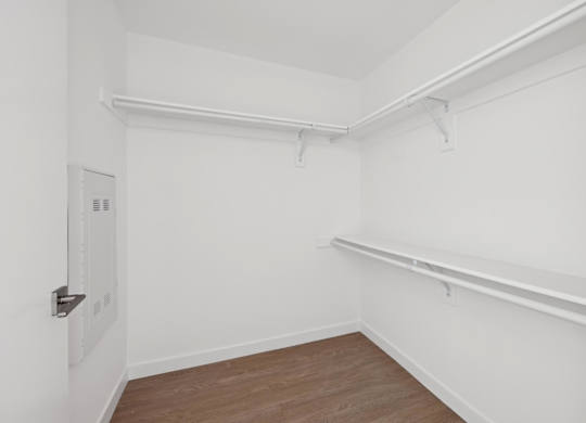 A white room with a door and a shelf.