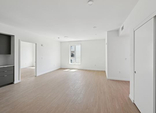 A spacious room with wooden flooring and white walls.