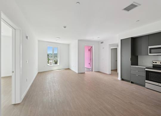 A spacious, empty room with a kitchen area to the right.