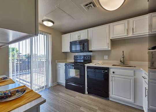 A modern kitchen with black appliances and white cabinets. at The Lex At Lowry, Denver