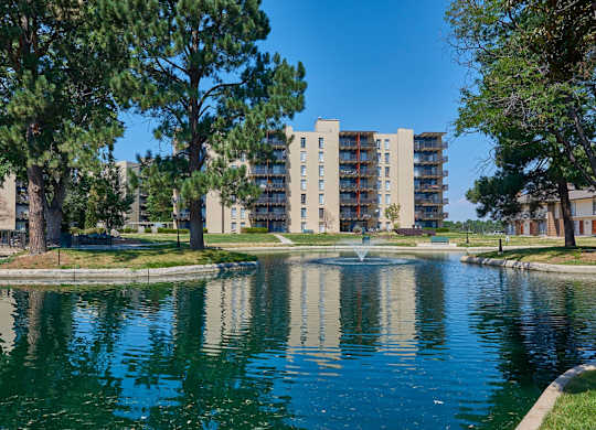 A pond in front of a residential building surrounded by trees. at The Lex At Lowry, Denver, Colorado