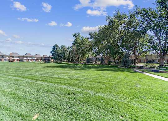 A grassy field with trees and houses in the background. at The Lex At Lowry, Denver, 80224