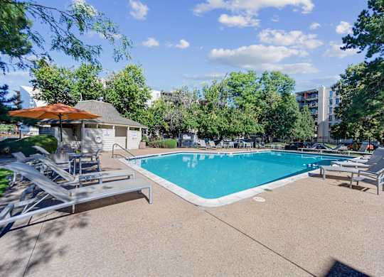 A swimming pool surrounded by trees and a building in the background. at The Lex At Lowry, Denver, Colorado