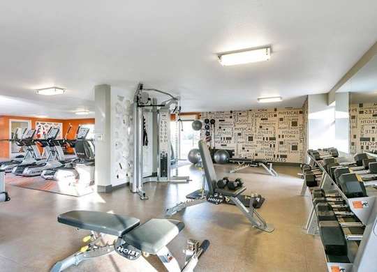 A gym with a variety of equipment including treadmills, weights, and exercise machines. at The Lex At Lowry, Denver