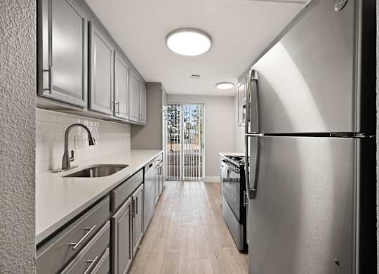 A modern kitchen with stainless steel appliances and wooden floors. at The Lex At Lowry, Denver, CO
