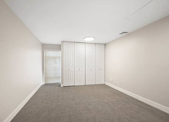 A room with a grey carpet and a white wardrobe. at The Lex At Lowry, Denver, Colorado