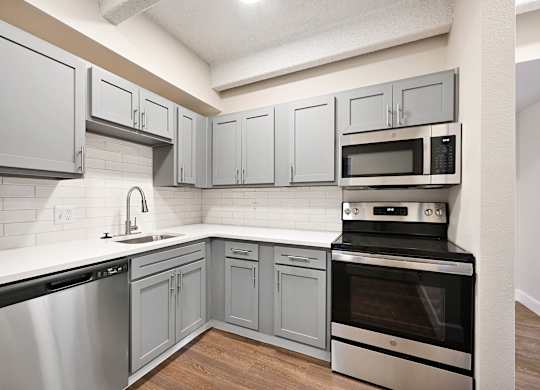 A kitchen with a stainless steel dishwasher and oven. at The Lex At Lowry, Denver, 80224